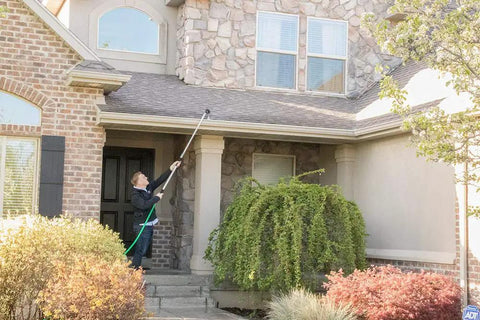 Person using 2-Pack Telescoping Watering Tool With Five-Position Pole Extending From 3.5 To 6 Feet, Four Spray Patterns to clean roof