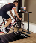 Person cycling indoors using Adjustable Treadmill Desk With Walking Pad Stand For Home Office And Bike Trainer A Versatile Standing Workstation