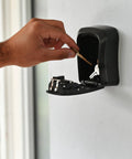 Hand placing keys into Heavy-Duty Key Lock Box Wall Mount with 4-Digit Combination, Waterproof Metal Safe for Outdoor Access