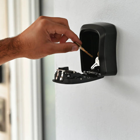 Hand placing keys into Heavy-Duty Key Lock Box Wall Mount with 4-Digit Combination, Waterproof Metal Safe for Outdoor Access