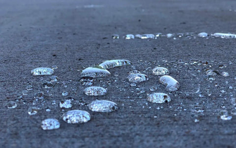 Water droplets forming on a concrete surface treated with Tough As Nails Penetrating Concrete Sealer For Driveways And Retaining Walls Breathable Moisture Shield Keeps Slabs Dry No Sweat Waterproof Cover Pro Grade Construction Ready Five Gallon Bucket.