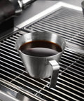 Two Piece Stainless Steel Espresso Cups With Handles And A Pro Pour Double Spout Measuring Cup With Dual Scale V Shaped Mouth For Drip Free Espresso Shots 3.4 Oz 100 Ml Silver on a metal grating