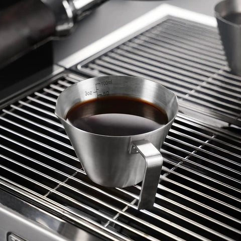 Two Piece Stainless Steel Espresso Cups With Handles And A Pro Pour Double Spout Measuring Cup With Dual Scale V Shaped Mouth For Drip Free Espresso Shots 3.4 Oz 100 Ml Silver on a metal grating
