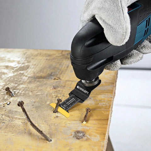 Front view of a black-blue oscillating multitool with a titanium blade cutting nails from a wooden board.