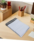 Stack of Self-Seal White Poly Mailer Bags 100 Pack 10x14 Inches Waterproof And Tear-Resistant Shipping Bags for Clothes on a desk