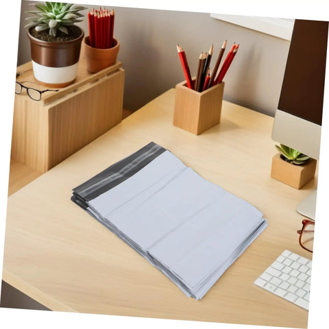Stack of Self-Seal White Poly Mailer Bags 100 Pack 10x14 Inches Waterproof And Tear-Resistant Shipping Bags for Clothes on a desk