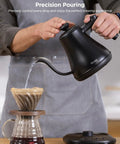 Smart Electric Kettle With WiFi And Alexa Control For Home Baristas Gooseneck Pour Over Kettle With Variable Temperature 1200W Quick Heat 0.8L Capacity One Hundred Percent Stainless Steel Matte Black shown pouring water over coffee dripper.