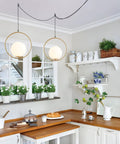 Plug In Globe Pendant Light Fixture With White Glass Ball And Brushed Brass Ring in modern kitchen setting