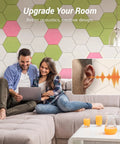 Couple with laptop on couch, wall with 12 Pack High Density Hexagon Acoustic Panels For Serious Noise Reduction With 0.9 NRC Peel And Stick Wall Decor