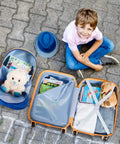 Two Piece Kids Luggage Set With 12 Inch Backpack And 18 Inch Rolling Suitcase In Blue Astronaut Design Lightweight Durable ABS Hardshell Kid Friendly Carry On Travel Gear For Boys And Girls shown opened with toys and books.