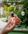 Hands installing LED Outdoor String Lights 109 Ft With 52 Edison Shatterproof Bulbs Plus 2 Spares, Dimmable, Energy Saving