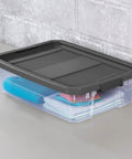 Box Stacker Modular Clear 40 Quart Storage Bin For Easy Organization And Space Saving Stackable See Through Plastic Container With Durable Build And Latching Lid No Fuss Garage Pantry And Closet 14743V06 with black lid, storing items inside, on a gray surface.