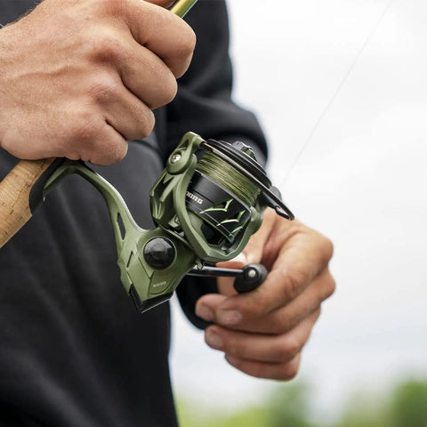 Spartacus II Spinning Reel Sealed Carbon Fiber Build 22 Lb Max Drag 7 Plus 1 Stainless Bearings Five Point Two To One Gear Ratio Saltwater And Freshwater Ready Size 500 And 1000 For Ice Fishing. Angler holding reel for freshwater and saltwater use.