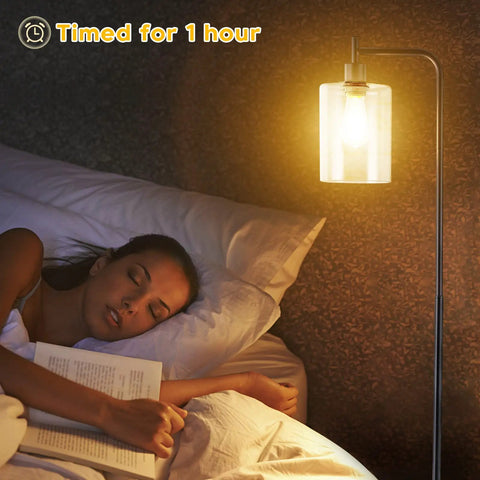 Lit Industrial Floor Lamp In Black And Gold With Clear Glass Shade next to woman sleeping
