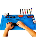 Hands using Pro Grade Large Silicone Soldering Mat With Magnetic Parts Layout Built In Ruler for Electronics Computer Repair 21.6 By 13.8 Inches Heat Resistant Insulation Soldering Station Pad With 124 Screw Positions 4 Magnetic Areas 18 Notches 49 Spare Units surrounded by tools on blue mat