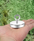Heavy Duty Silver Fishing Magnet 2.0 Inch With Eyebolt Handle 350lb Neodymium Pickup Magnet in hand on greenery background
