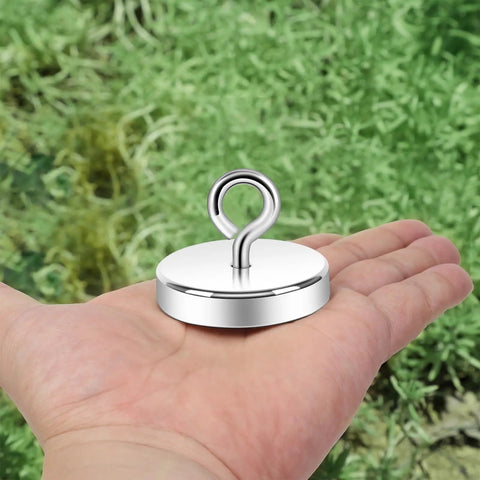 Heavy Duty Silver Fishing Magnet 2.0 Inch With Eyebolt Handle 350lb Neodymium Pickup Magnet in hand on greenery background