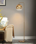 Gradient Gold Floor Lamp With Glass Globe LED Standing Light In Modern Mid Century Style beside couch in a living room.