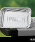 Aluminum Drip Pans 10 Pack For Gas Grills Indirect Grilling And Grease Catching Ideal For Roasts Turkeys And Gravy Drippings Easy Cleanup Disposable Foil Pans For Grill Trays stacked on a grill side shelf