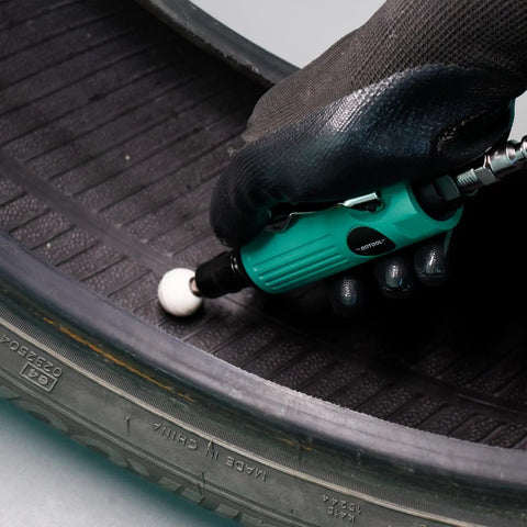 Close-up of Straight Shooter Air Die Grinder Kit being used on a tire, showcasing pneumatic polishing while wearing gloves.