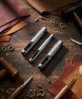 Pro Grade Heavy Duty Steel Leather Hole Punch Set Three Piece Grommet Punch Kit With Sizes One Quarter Inch Three Eighths Inch And One Half Inch For Leather Craft Belts Bags Upholstery And DIY Projects displayed on a wooden table with leather and tools.