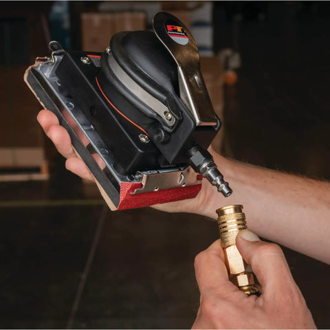 Top Shelf Pneumatic Orbital Sander With Built In Air Regulator And Rubber Over Mold Grip in hand connecting air hose.