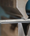 Close-up of 4 Pcs Hot Rolled ASTM A36 Steel Plates Half Inch Thick 4X4 Inch in a metal press for drilling and welding DIY metalworking.