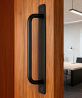 Side view of Two Pack Sliding Barn Door Handle With Plate, 7 Inch Aluminum Alloy Door Pull, Black Finish, installed on a wood door.