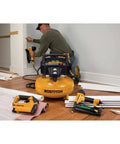 Man using Garage Ready 0.8 HP 6 Gallon Oil Free Pancake Air Compressor in home shop with tools for DIY project, compact design.