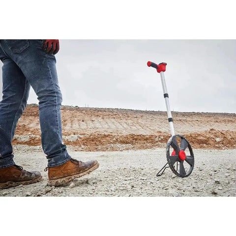 New 48-22-5112 for Milwaukee 12 In. Digital Measuring Wheel Red/Black alongside a person walking on a gravel path.