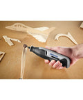 Hand holding Ultra Compact Four Volt Cordless Rotary Tool Featuring Variable Speed And No Sweat Accessory Swaps for crafting wood models.