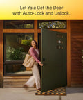 A woman entering a home through a modern door featuring the Slick Satin Nickel Smart Deadbolt Featuring Bump Proof Touchscreen Keypad.