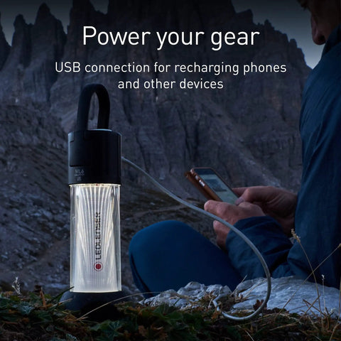 ML6 Camping Lantern With Micro Prism LED illuminating a mountain campsite, USB cable attached to a phone for charging
