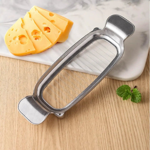 Heavy Duty Real Deal Butter And Cheese Slicer With Precision Stainless Steel Wires Ergonomic Grip next to sliced cheese.