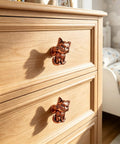 Hella Adorable 3D Sitting Cat Cabinet Knobs Four Pack Vintage Metal Drawer Pulls For Kitchen Cabinetry Upgrades With Embossed Fur Texture And A Super Chill Vibe To Liven Up Your House Today, showing bronze cat knobs on a light wood dresser.