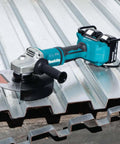 Kickass 36V Brushless Angle Grinder And Cut Off Tool With 9 Inch Blades on metal roofing, showcasing dual 18V batteries and cutting disc.