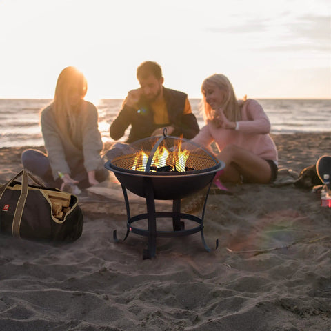 Beach scene with Extra Large Fire Pit BBQ Grill Bowl with mesh screen, tote bag, and friends enjoying a bonfire.