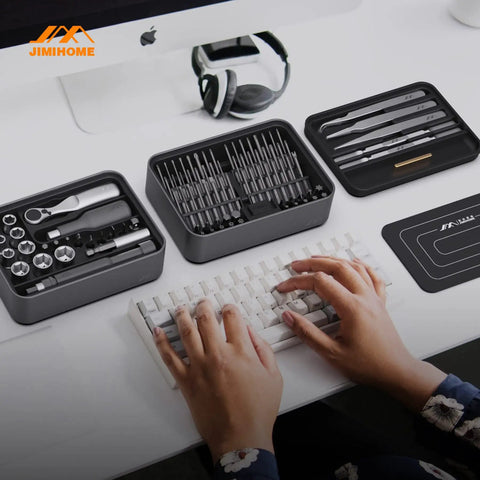 Hands typing near One Hundred Piece Precision Screwdriver Set With Ratchet And Magnetic Tweezers For Electronics PCs Laptops And Tablets DIY Friendly Desktop Mini Tool Station With Bits For Repair And Household Fixes.