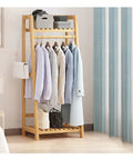 Kickass Foldable Heavy Duty Garment Rack Free Standing Closet Organizer with hanging shirts and storage bins in a bedroom.