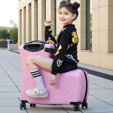 Pink kids ride-on suitcase with wheels; child sits on it outdoors.