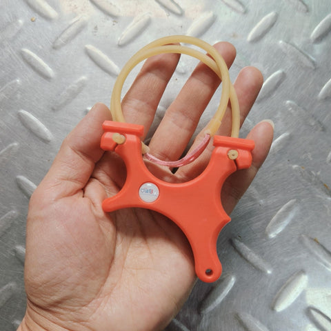Ultra Compact Mini Slingshot With Flat And Round Bands In Red Nylon Fiber, Ambidextrous And Pocket Sized, held in hand for size reference.