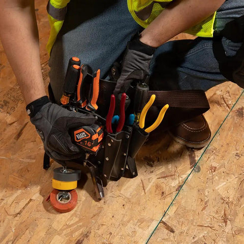 Worker using sturdy leather tool pouch with eleven pockets for belt up to two and three quarters inches moisture resistant