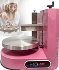 Pink automatic cake coating and smoothing machine for home or bakery with LCD, shown near decorated cake.