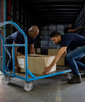 Workers loading boxes onto a cart with industrial caster wheels. Cart uses Industrial Caster Wheels Pack Of Four Three Inch By One And A Quarter Inch Sintered Iron Wheels 350 Lbs Capacity Per Wheel Beefed Up Cart Dolly Casters High Temperature Range Minus Forty To Five Hundred Fahrenheit Long Wearing And High Load.