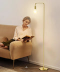 Industrial Floor Lamp With Light Bulb Included, tall standing light in brushed gold next to a woman reading on a beige sofa