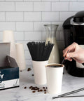 Skinny Black Plastic Sip Stirrer Straws For Coffee And Cocktails, Seven And A Half Inch Stirrers in coffee next to box