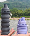 Two Pack Collapsible Silicone Water Bottles 500ml Each, Purple and Grey, held with mountaineering buckles, outdoor background