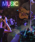 Music Neon Sign LED Wall Light Neon Letters For Bedroom Game Room Bar Club Party Decor Colorful Mood Lighting Perfect For Home Christmas Party And Holiday Lit Vibe glowing above musicians playing guitar and drums on stage.