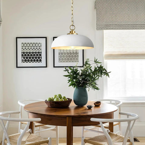 Top Shelf Matte White Farmhouse Pendant Light With Burnished Brass Accents illuminating a dining table with greens and decor.