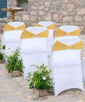 Front view of white banquet chairs with gold spandex chair sashes and ring sliders.